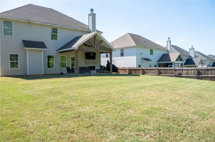 This residence features a large backyard with an inviting covered patio, perfect for outdoor living.