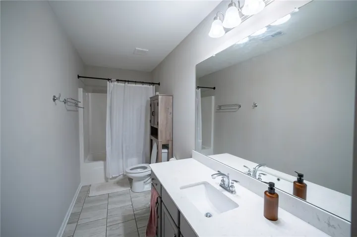This clean and bright bathroom features a single vanity with ample counter space and a bathtub with a shower.