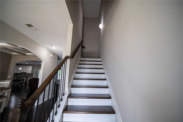 This spacious foyer with a grand staircase offers a welcoming entry to the home's open floorplan.