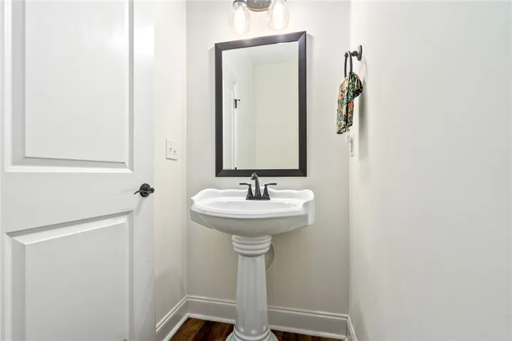 This clean and bright powder room features a classic pedestal sink and ample lighting.