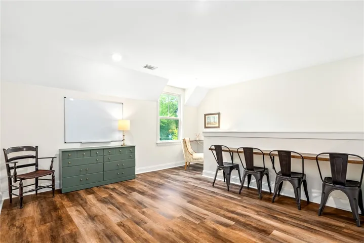 This bright room features durable flooring and sloped ceilings, perfect for a versatile living space.