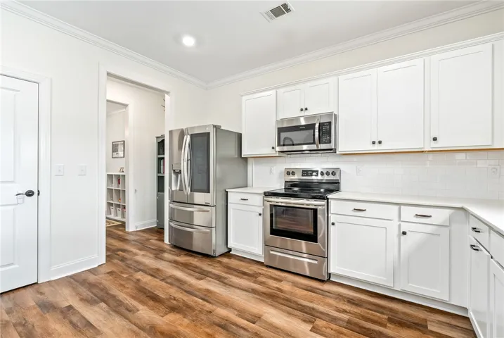 This bright kitchen features white cabinetry and stainless steel appliances, creating a fresh, inviting atmosphere.