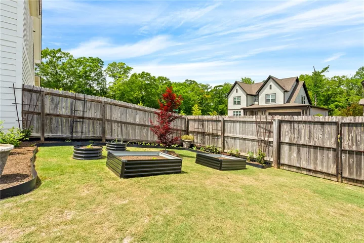 This spacious yard features raised garden beds and a sturdy fence, perfect for outdoor living.