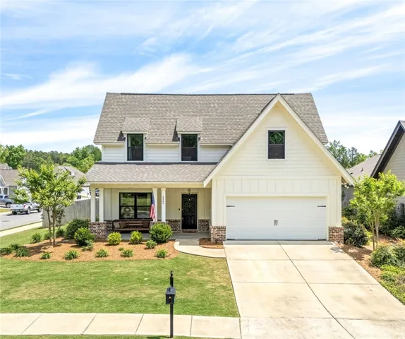 This inviting residence features a welcoming porch, lush landscaping, and a spacious driveway.