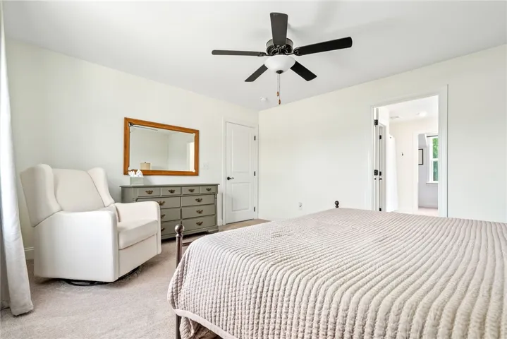 Bright and airy bedroom features soft carpet flooring, a ceiling fan, and convenient access to the ensuite bathroom.