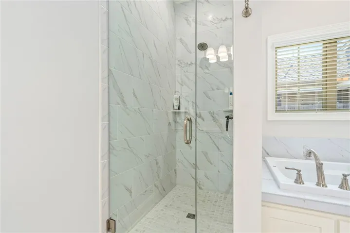 This primary bathroom features a tiled walk-in shower and a spacious built-in tub for relaxation.