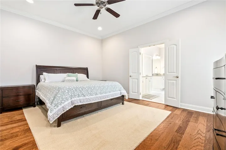 This primary bedroom offers warm hardwood flooring and high ceilings, creating a bright and airy retreat.