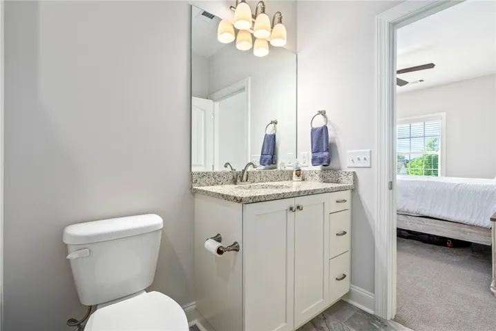 This bright bathroom features elegant granite counters and tiled flooring, offering both style and durability.