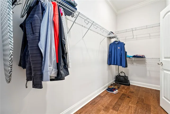 This primary closet features ample storage solutions and warm wood flooring.