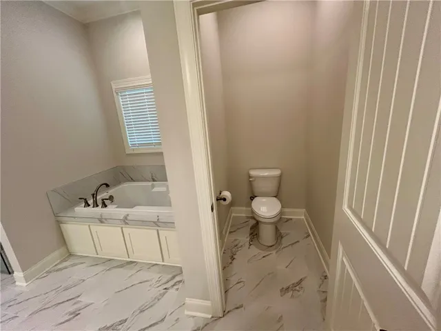 Relax in this tranquil bathroom featuring a soaking tub and elegant tile flooring.