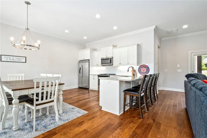 This spacious kitchen and dining area features rich hardwood floors and elegant crown molding.