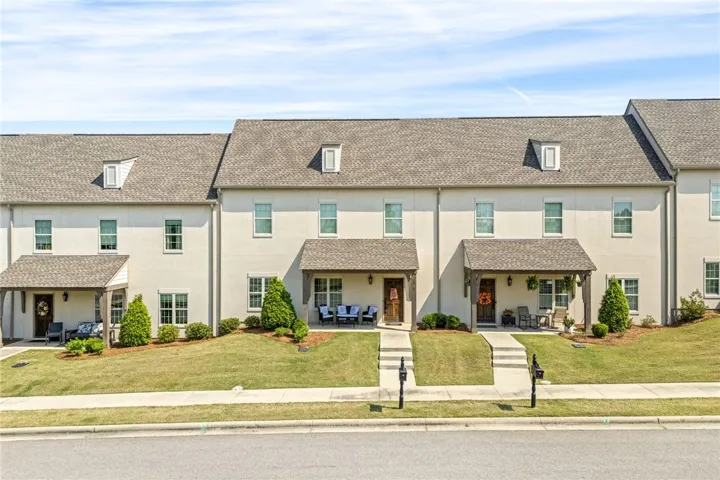 These charming townhomes feature inviting front porches and lush green lawns, creating a welcoming facade.