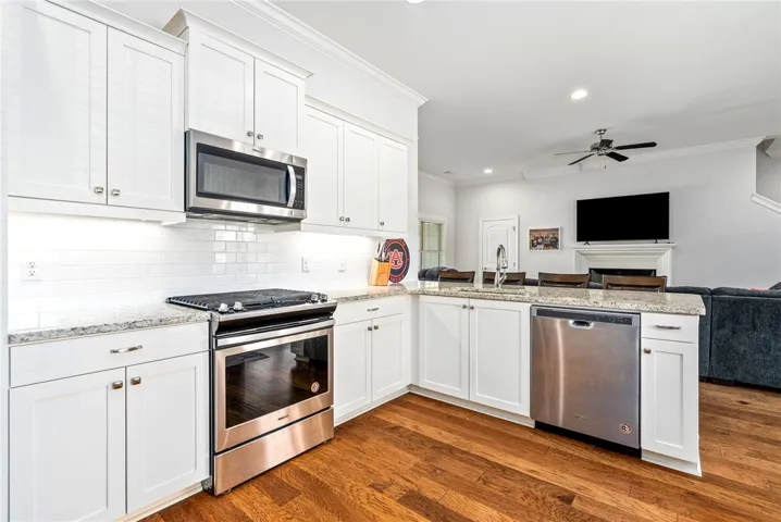 This bright kitchen features classic white cabinetry and rich hardwood flooring, creating an inviting atmosphere.