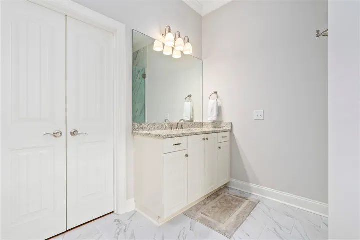 This bright bathroom features a vanity with granite counters and a large mirror.