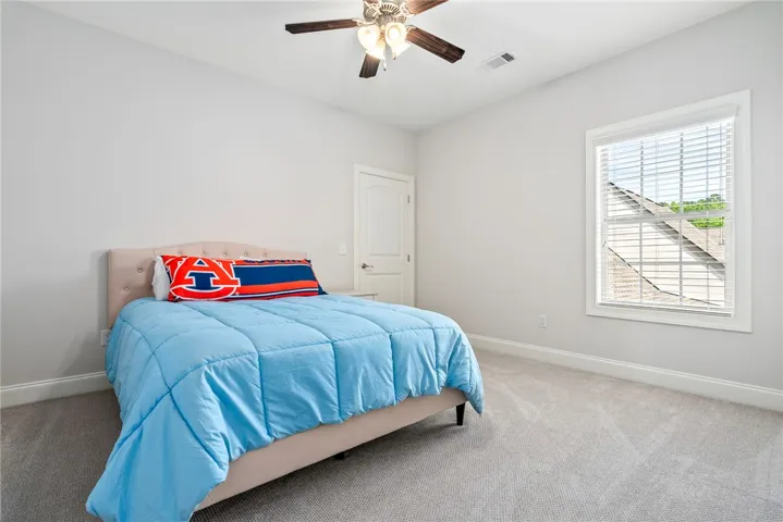 This cozy bedroom features a window and ceiling fan, offering comfort and natural light.