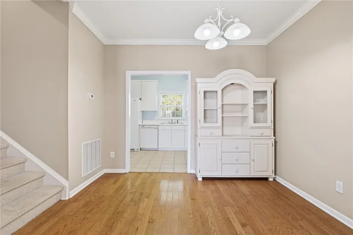 Bright dining area with elegant hardwood floors, crown molding, and a seamless transition to the kitchen.