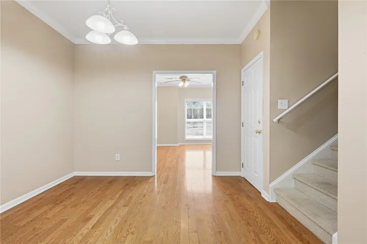 This inviting dining room showcases gleaming hardwood floors, crown molding, and a classic chandelier, offering a warm eating area.