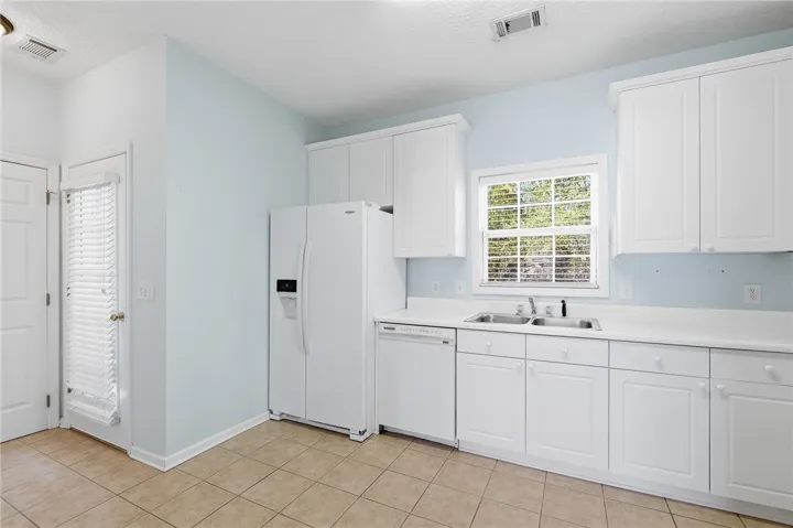 This bright kitchen features white cabinetry, ample counter space, and durable tile flooring. Access to the deck balcony.