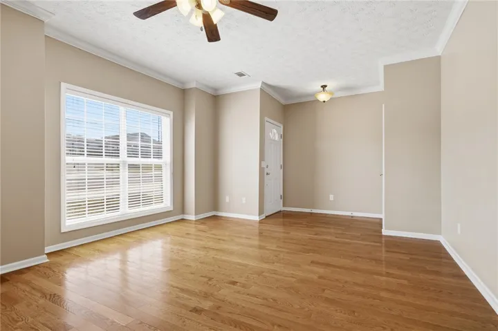This versatile living area features hardwood floors, crown molding, and a bright window, perfect for various layouts.
