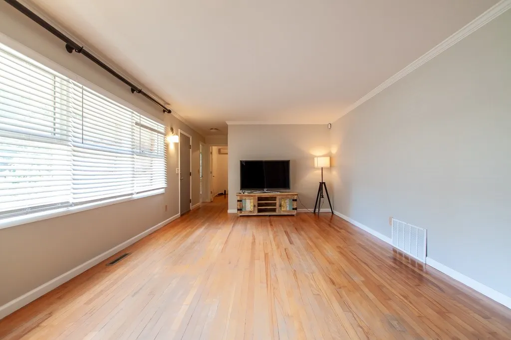 This sunlit living area boasts gleaming hardwood floors and ample natural light, perfect for everyday living.