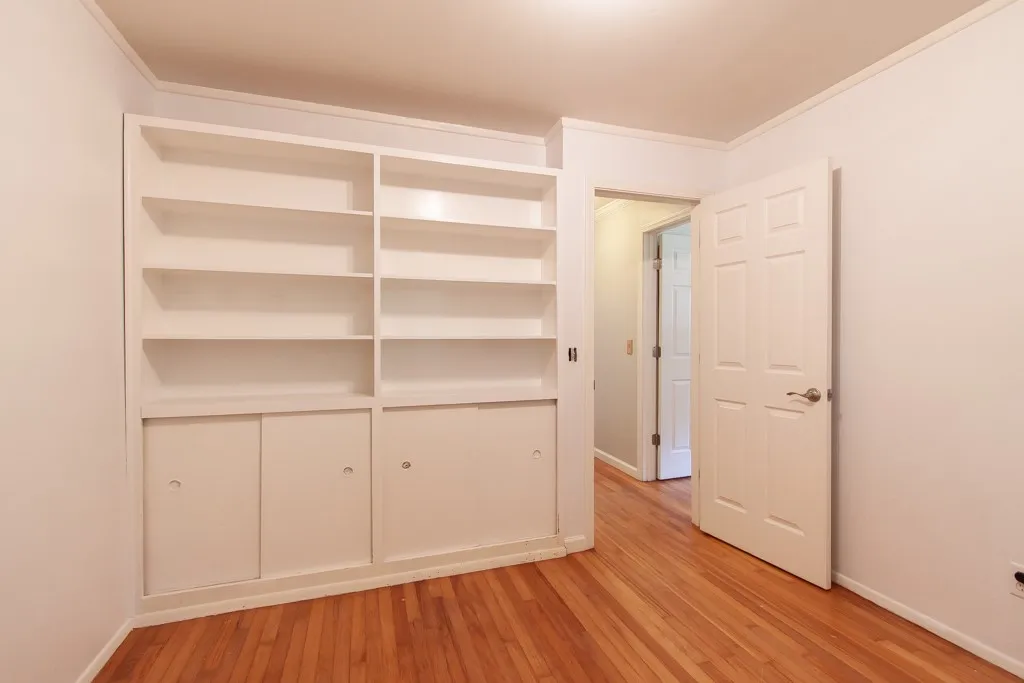 This versatile room features warm wood flooring and a built-in bookshelf for ample storage.