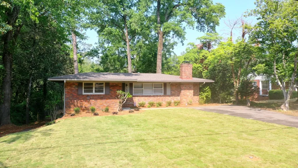 This classic brick residence features a lush lawn, mature trees, and a spacious front yard.