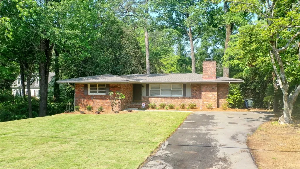 This classic brick residence features a lush lawn and mature trees, creating a serene setting.