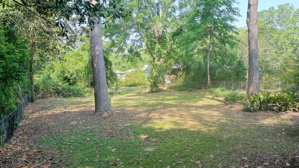 A spacious yard with mature trees offers a serene natural setting, perfect for outdoor enjoyment.