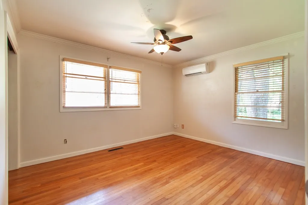 This airy room features rich hardwood flooring and a refreshing ceiling fan.