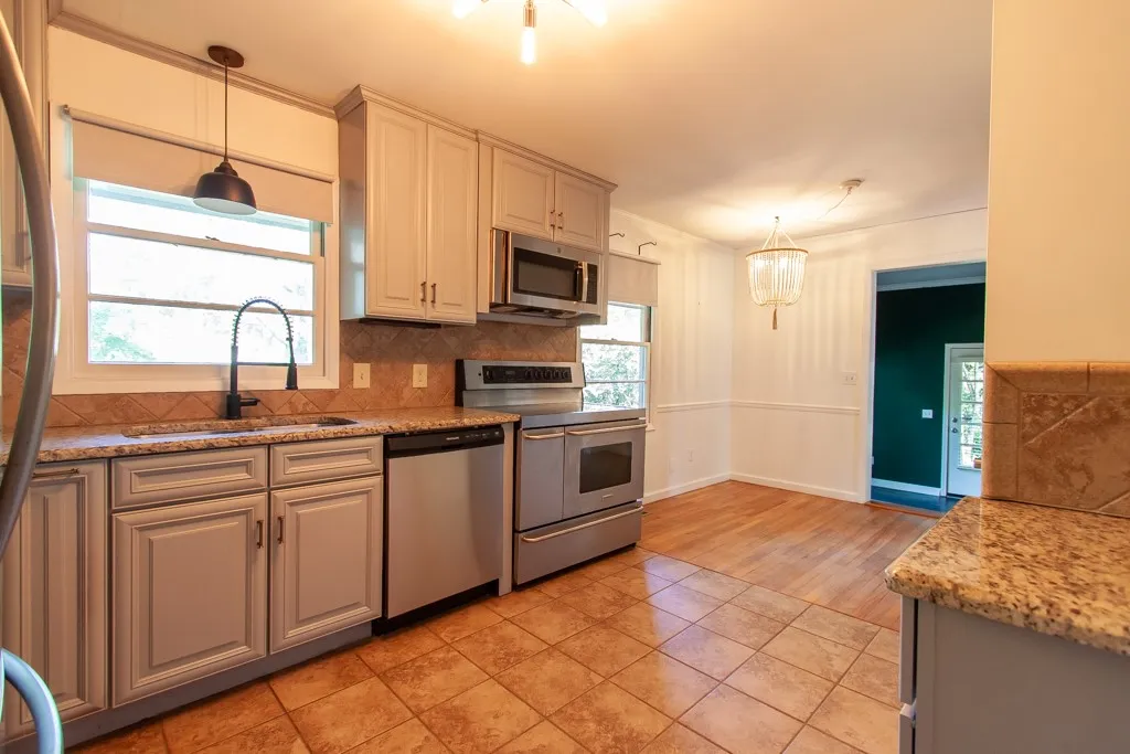 This bright kitchen features modern appliances, granite counters, and ample cabinetry, with an adjacent dining space.