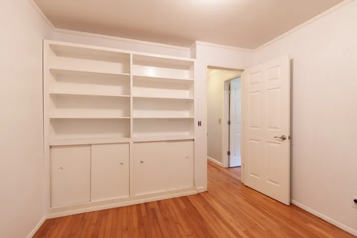 This versatile room features warm wood flooring and a built-in bookshelf for ample storage.