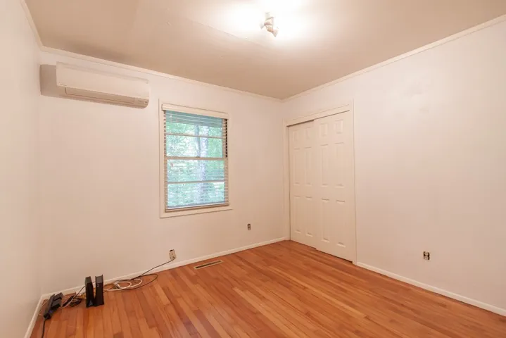 This spacious bedroom features lustrous hardwood floors and a window with natural light.