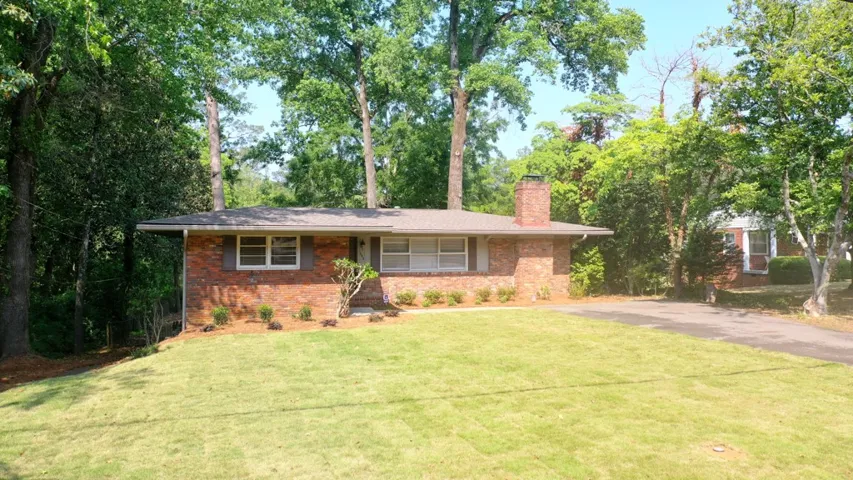 This classic brick residence features a lush lawn, mature trees, and a spacious front yard.