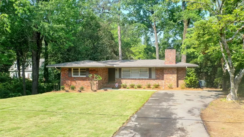 This classic brick residence features a lush lawn and mature trees, creating a serene setting.