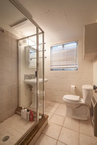 This functional bathroom features a tiled shower and pedestal sink, offering practicality and ease.