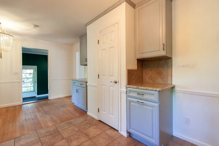 This bright kitchen area features functional cabinetry and a combination of tile and hardwood flooring.