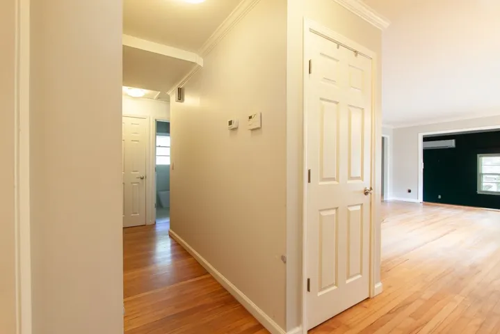 This spacious hallway features hardwood flooring and classic crown molding, offering a warm and inviting transition.