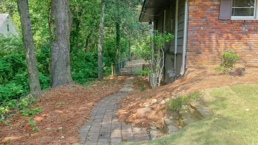 This property features a charming brick exterior with a pathway leading to a fenced garden.