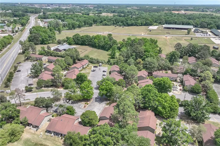 Expansive aerial view showcasing multiple structures nestled amongst lush greenery and open fields and close proximity to Auburn's campus.