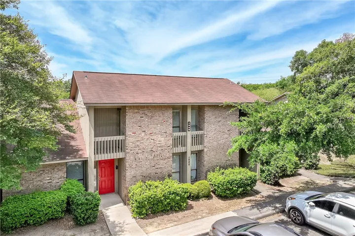 This charming residence features a classic brick exterior and an inviting red entry door.
