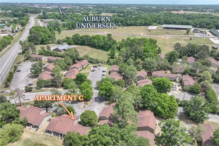 An aerial perspective showcases a residential community nestled among lush greenery, with proximity to academic grounds.