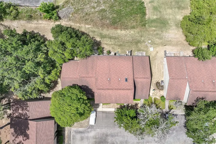 An aerial view showcases a residential property with lush trees and well-maintained grounds.
