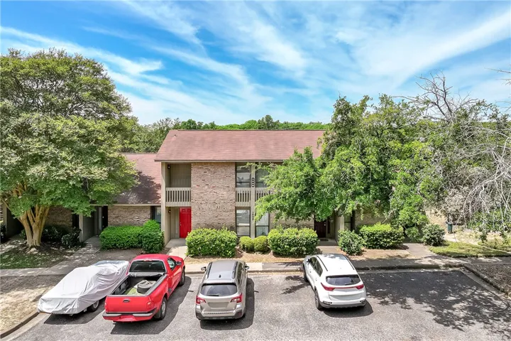 An inviting exterior of a multi-level brick residence with lush landscaping and convenient parking.