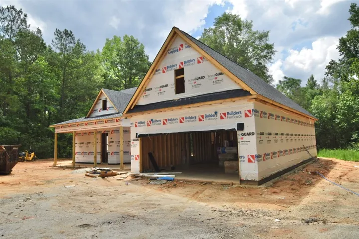 A new construction home with an attached garage features a classic gable roofline and a welcoming covered porch entry.