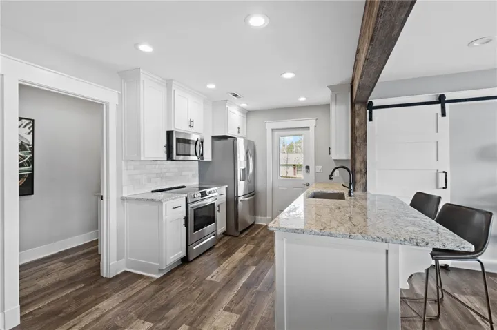 This modern kitchen features white cabinetry and granite countertops, with sleek stainless steel appliances.