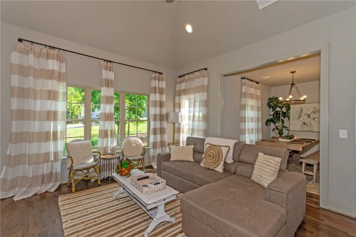 This inviting space features vaulted ceilings and hardwood floors, creating an airy and elegant living area.