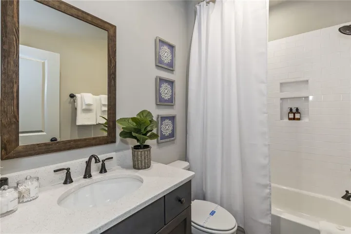This bathroom features a sleek vanity, a tub with a shower, and a minimalist design.