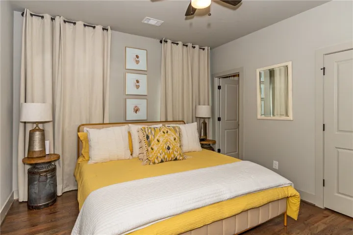 This cozy bedroom features warm wooden floors and a ceiling fan, ensuring comfort and style.
