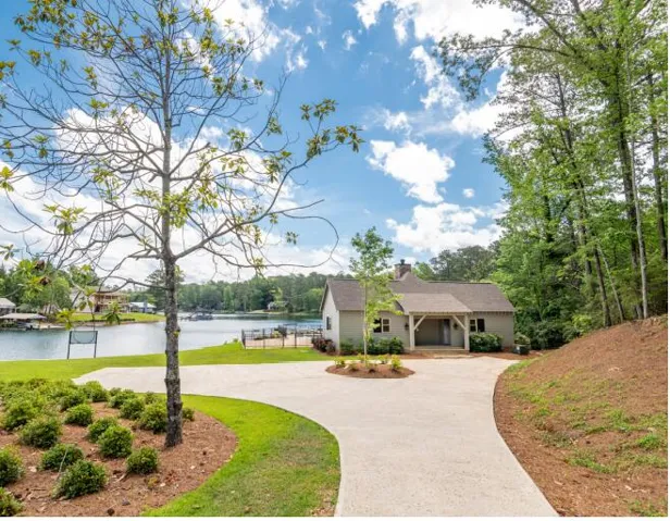 This captivating lakefront home features a charming exterior and a welcoming circular driveway.