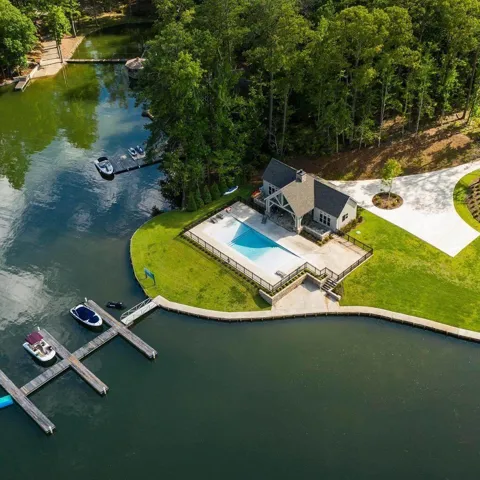 This exquisite waterfront property boasts a private pool, a boat dock, and lush green surroundings.